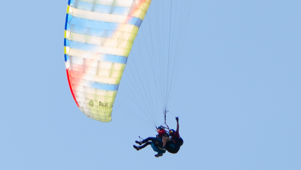 a tandem paraglider flying in the sunset light at Ca' del Monte